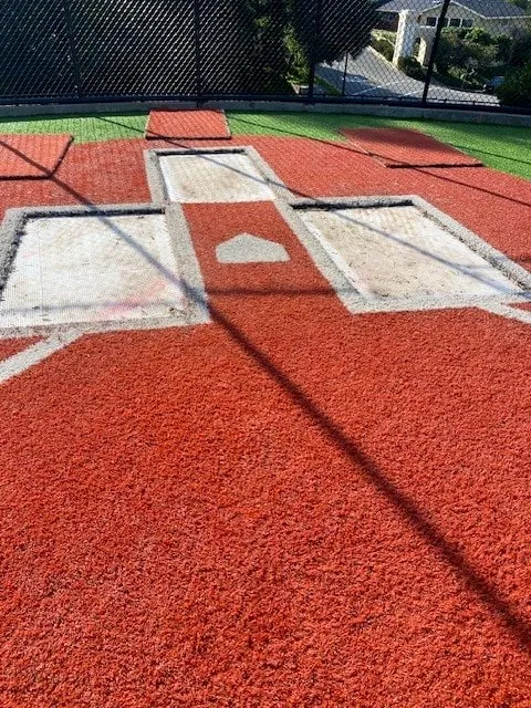 Worn white batter's boxes and catcher's box on red synthetic turf around home plate