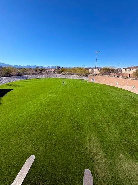 Large synthetic turf park field with mountains in the background