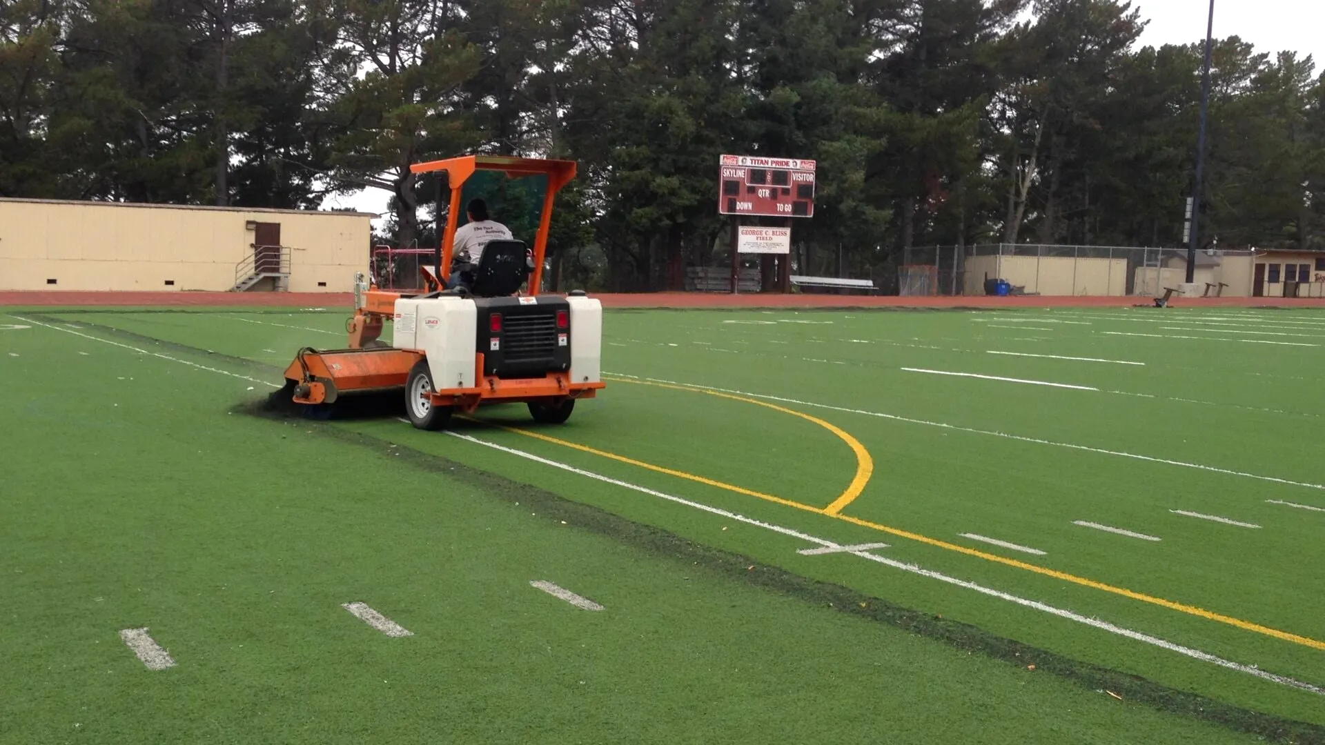Power grooming machine on a synthetic football field
