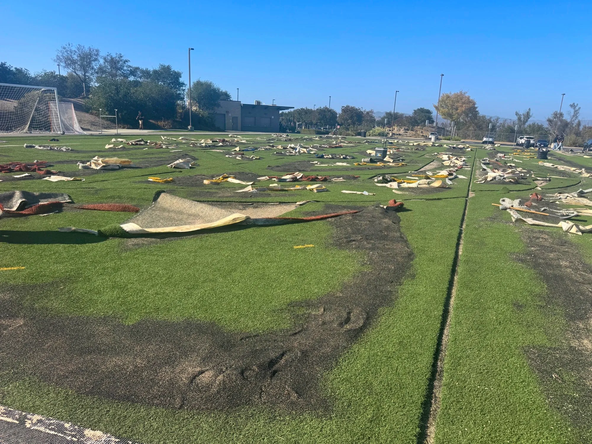 Turf panels pulled back along the seams across a synthetic soccer field during reseaming